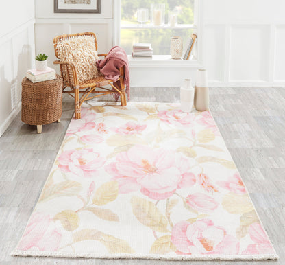 Floral pink peony area rug on light background, in a bright room with wicker chair, pink throw, and woven side table.