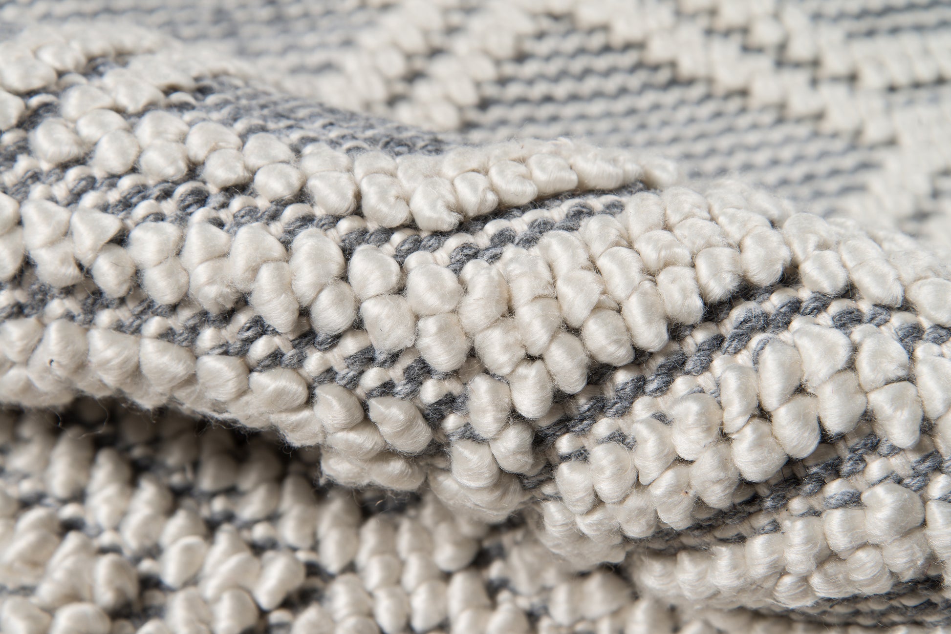 Close-up of a gray & cream loop-pile rug with chunky tufted yarns and woven texture.