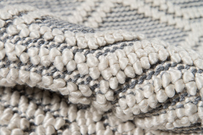 Close-up of a gray & cream loop-pile rug with chunky tufted yarns and woven texture.
