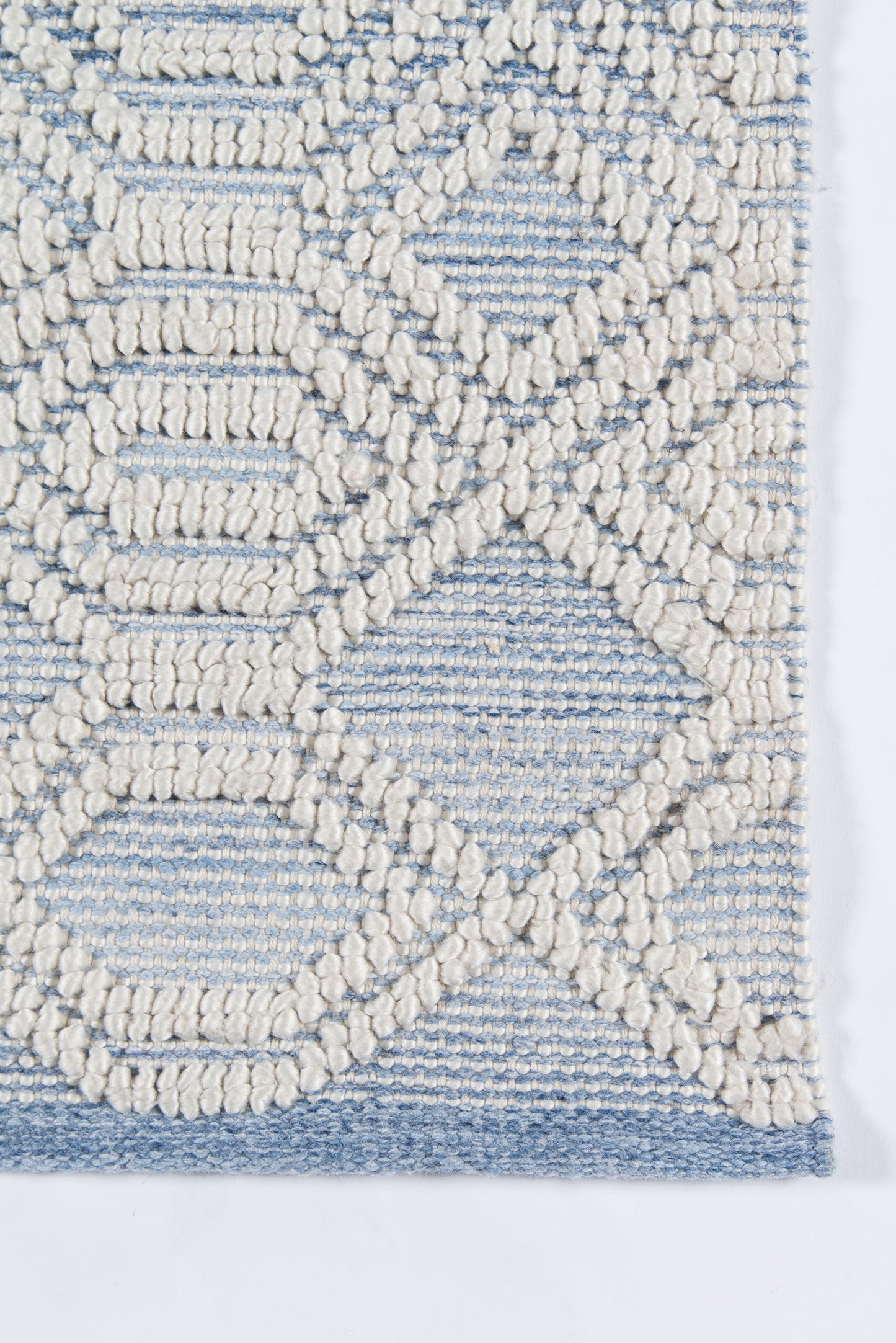Ivory boucle rug with raised geometric lattice pattern on pale blue base; blue border.