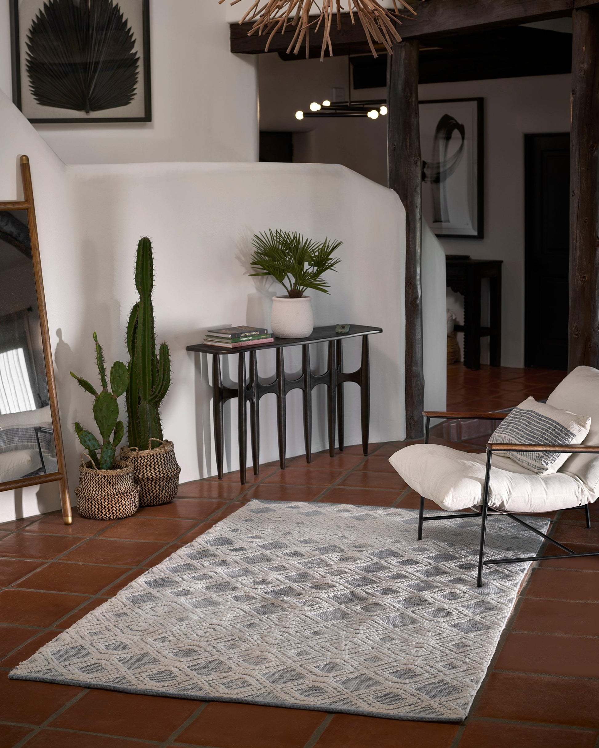 Light gray diamond-pattern rug runner in a boho living room with terracotta floor and potted cacti.