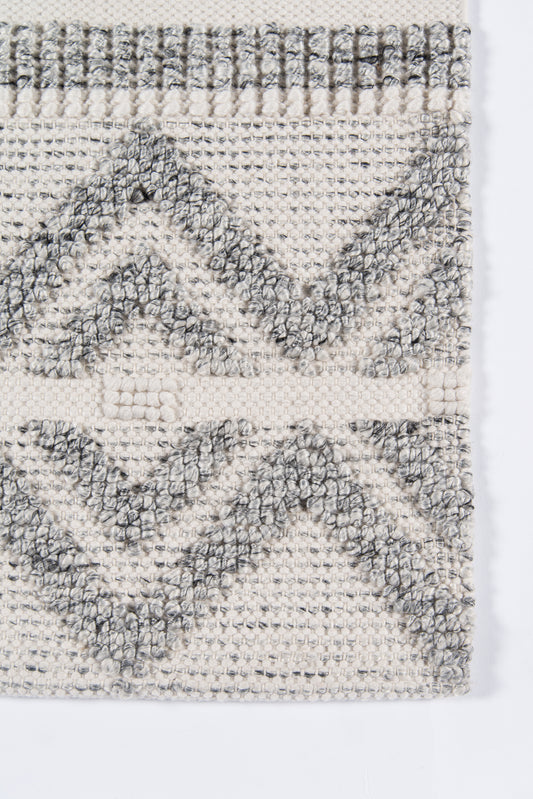 Cream woven rug with gray diamond chevron pattern, textured loop-pile, fringe border at top.