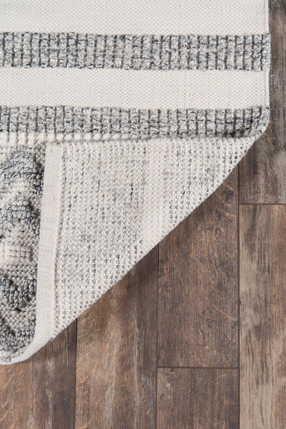 Beige-gray woven area rug with textured loop pile and striped border, folded corner showing underside on wood floor.