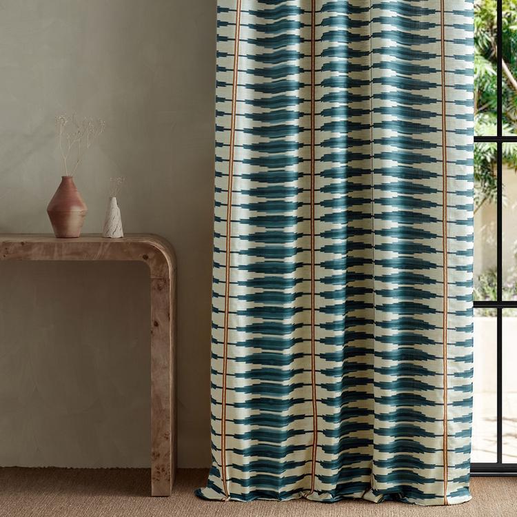 Harlequin Cintilla Denim Rust fabric with printed ikat stripe and embroidered stitch detailing in denim blue and rust tones, luxurious designer textile perfect for drapery, cushions, wall panels, and bold home décor projects.