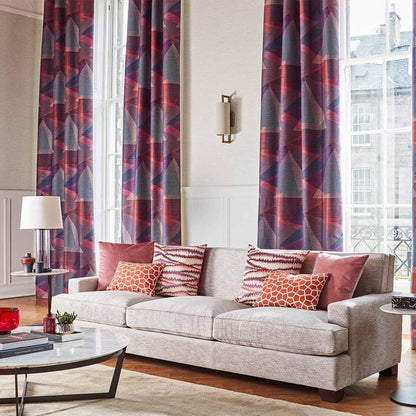 Modern living room: light gray sofa with orange geometric cushions, purple Harlequin curtains, and marble coffee table on wood floor