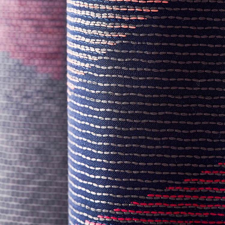 Close-up navy harlequin woven fabric with white dashed stripes, pink gradient edge and red accents.