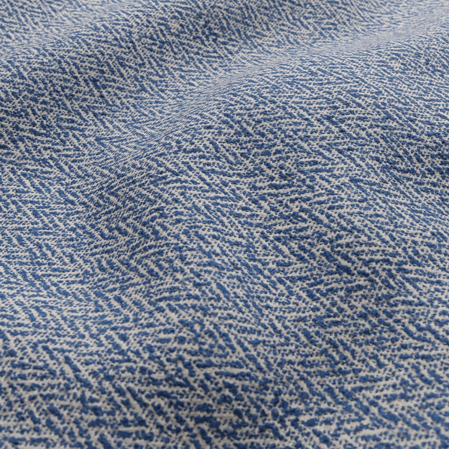 Close-up of blue and ivory bouclé outdoor fabric with a geometric textured pattern.