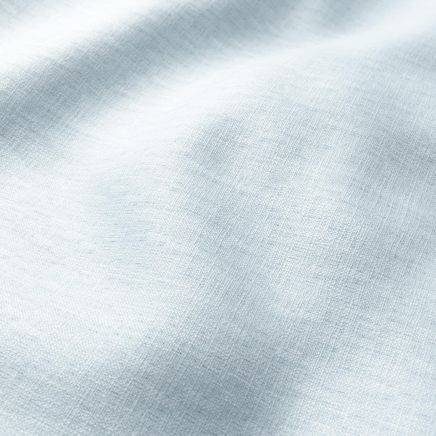 Light blue linen fabric close-up with soft wrinkles and natural texture, draped and versatile for apparel or decor.