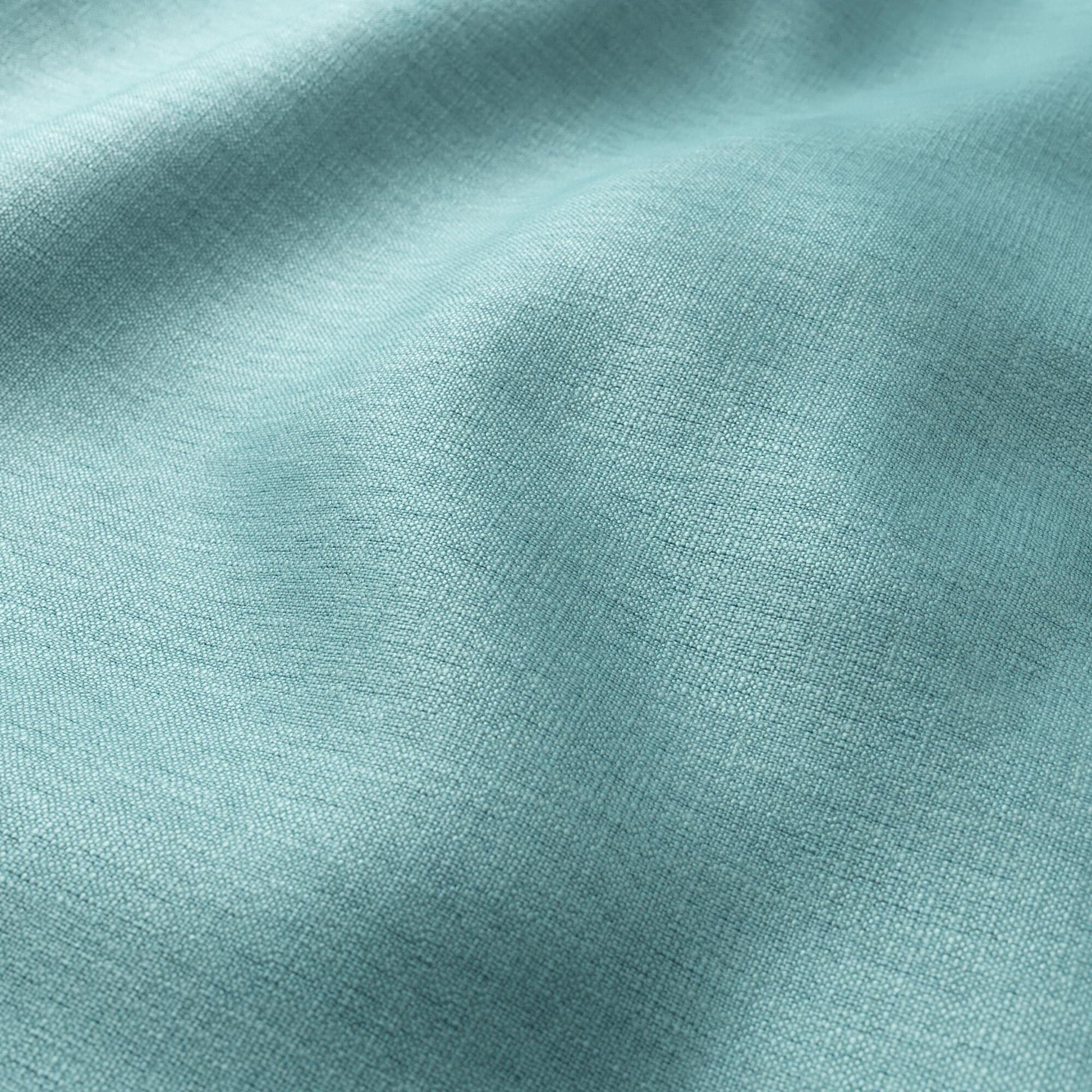 Teal linen-like fabric close-up, visible weave and soft drape.