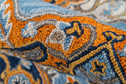 Close-up of a thick-pile tufted wool rug in orange, blue & gray geometric pattern.