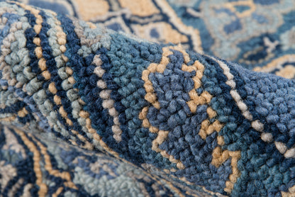 Close-up of a blue textured rug with navy, teal yarns and beige geometric patterns.