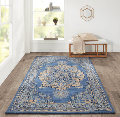 Rectangular blue Persian-style area rug with ivory/beige medallion pattern on wood floor in bright living room.