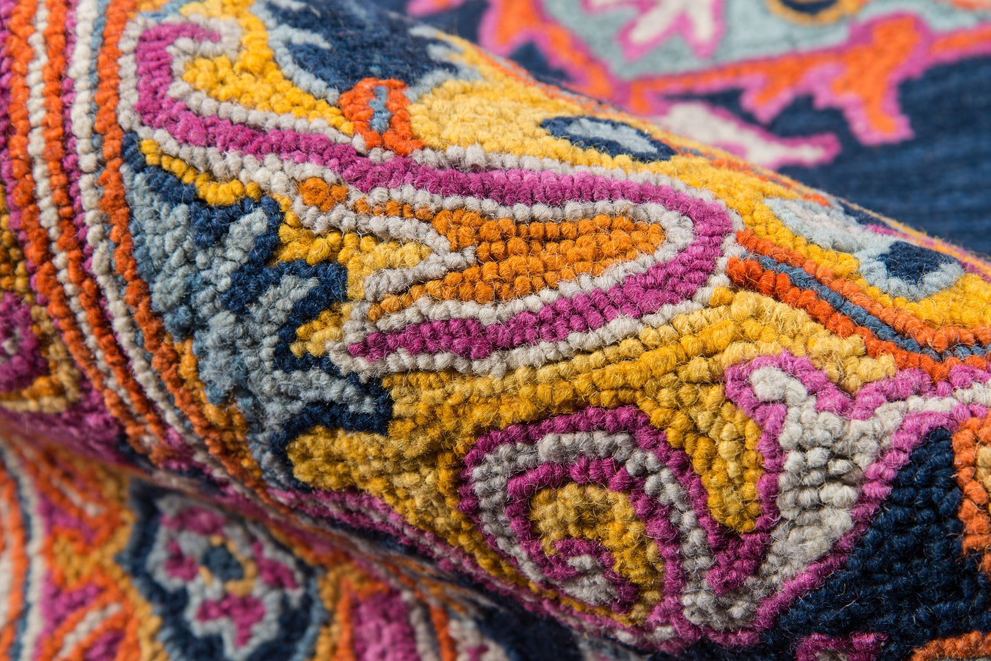 Close-up of a vibrant tufted rug runner with orange, pink, yellow, navy and teal geometric patterns.
