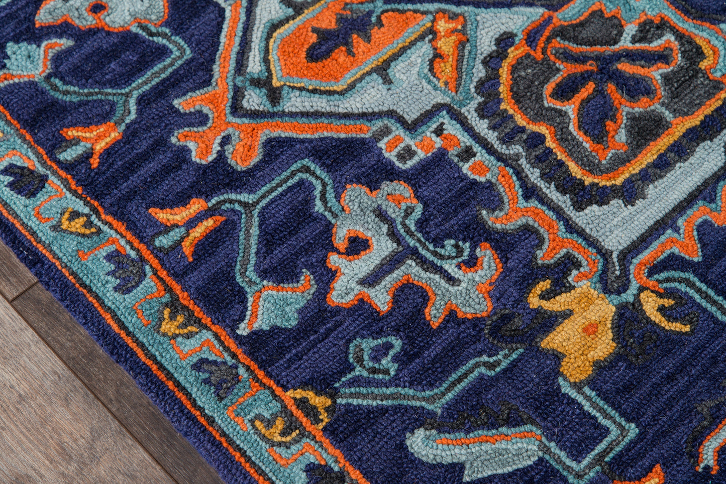 Ibiza-style navy rug with orange and teal floral-geometric pattern; plush texture, bordered edge on wood floor.