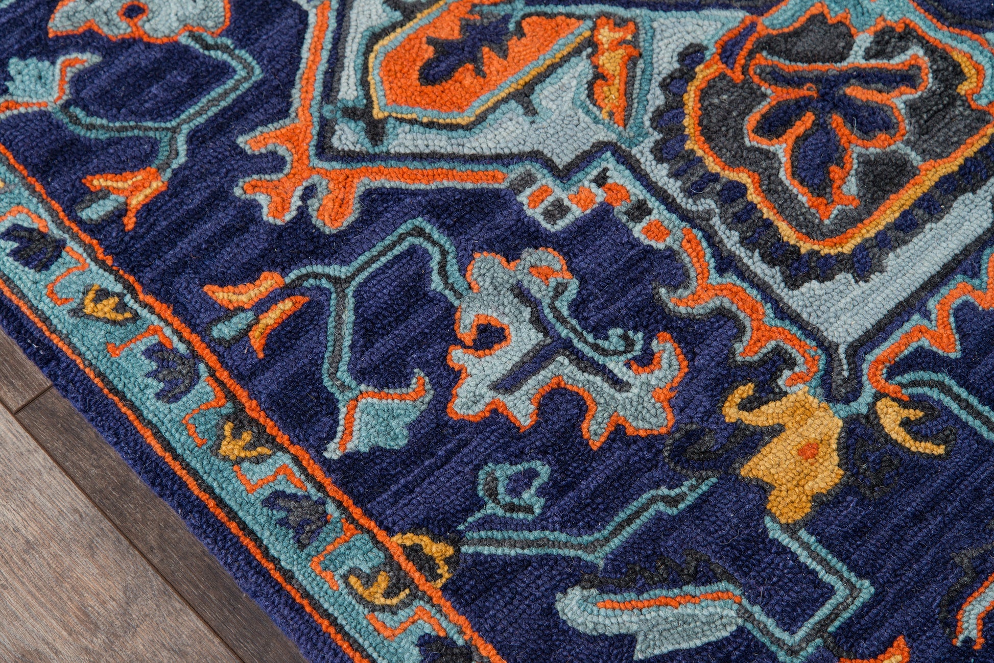 Ibiza-style navy rug with orange and teal floral-geometric pattern; plush texture, bordered edge on wood floor.