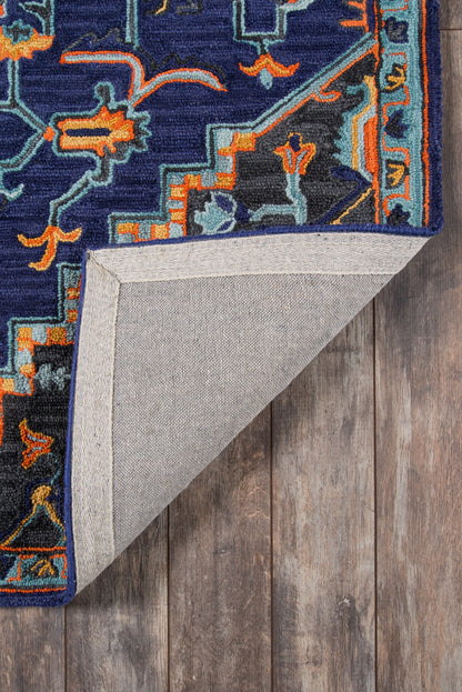 Navy blue oriental rug with orange and teal accents; folded corner reveals light gray backing on a wooden floor.