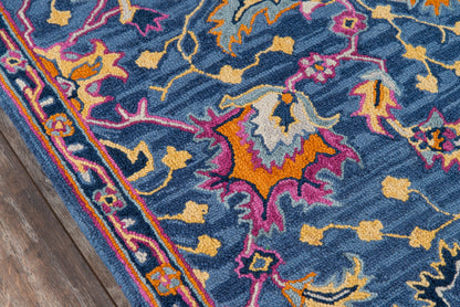 Blue Ibiza-inspired rug with vivid pink, orange and yellow florals and a decorative border on a wood floor.