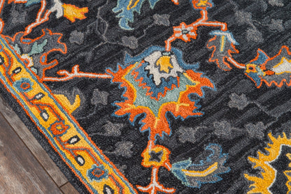 Dark ornate rug with vivid orange, teal and blue floral motifs and a yellow border on a wooden floor.