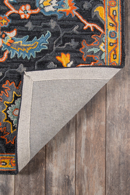 Ibiza-style oriental rug with dark background and blue, orange, yellow motifs; folded corner shows gray backing.