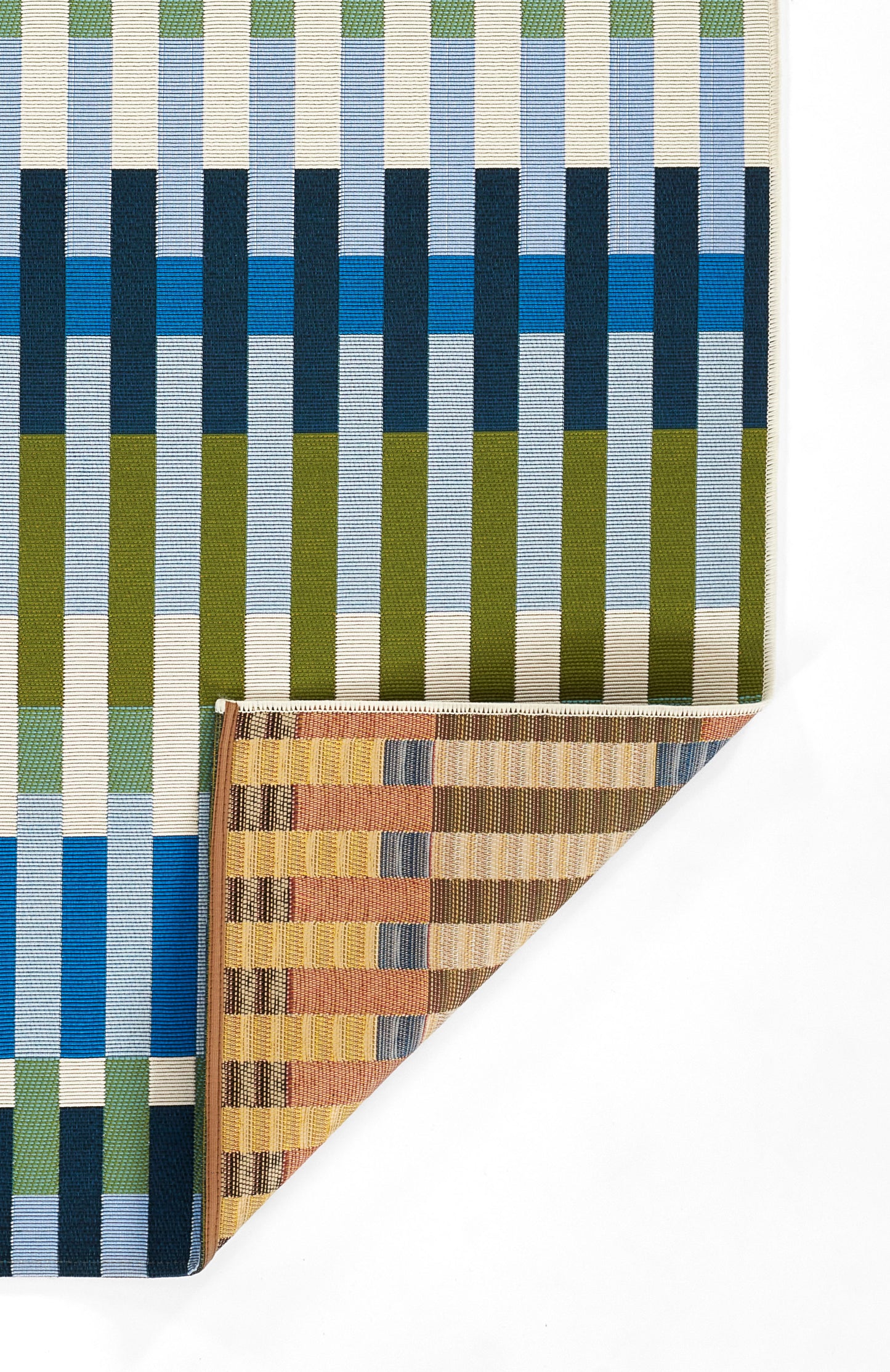 Woven rug with bold vertical stripes in blue, cream, olive and teal; folded brown-striped swatch at corner.