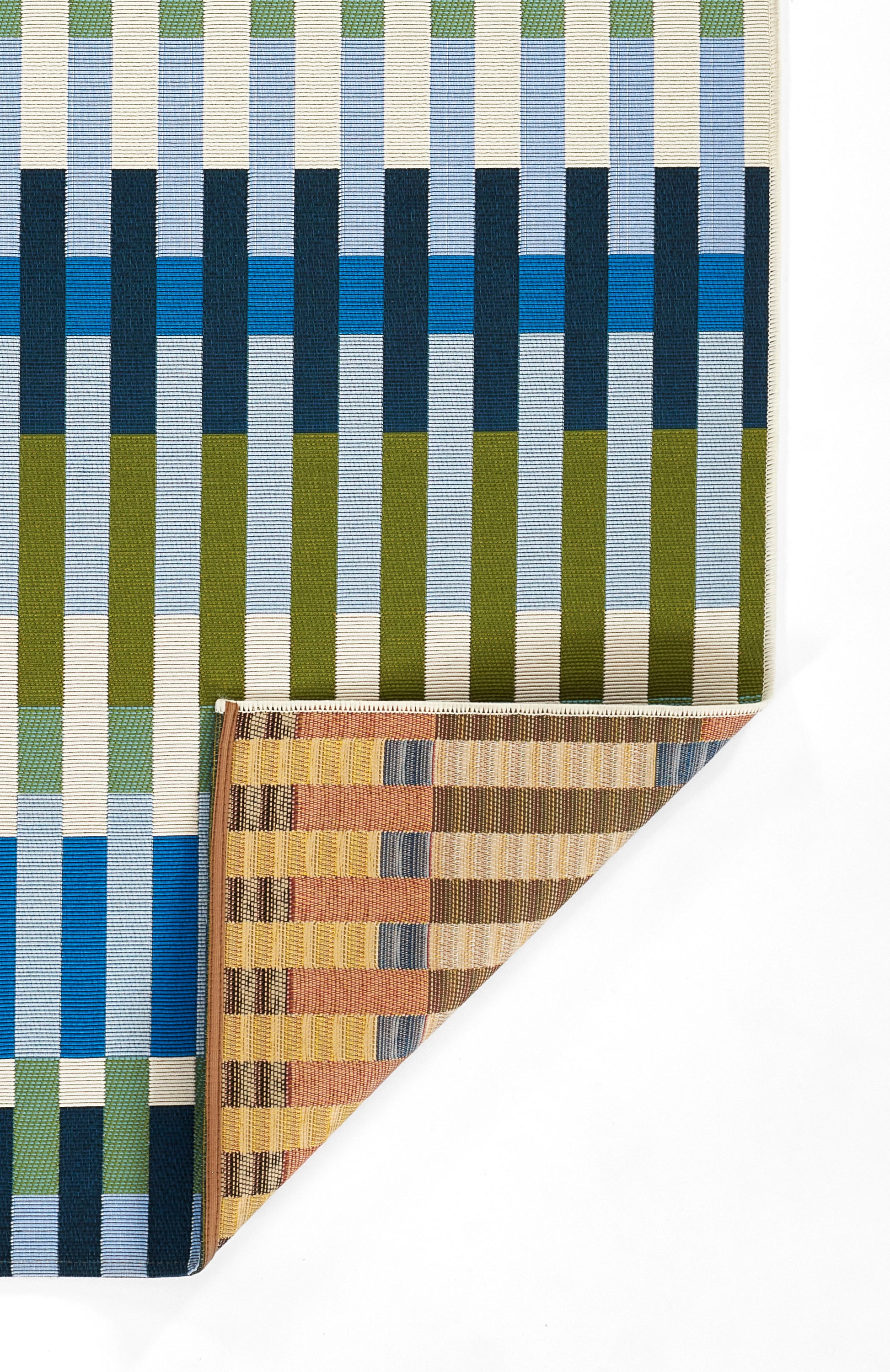 Woven rug with bold vertical stripes in blue, cream, olive and teal; folded brown-striped swatch at corner.