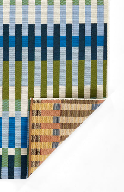 Woven rug with bold vertical stripes in blue, cream, olive and teal; folded brown-striped swatch at corner.