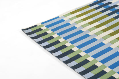 Woven rectangular rug in blue, olive green, cream & gray blocks forming a geometric striped checker pattern; modern rug.