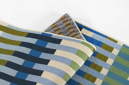 Woven rug with blue, olive and beige striped blocks in a geometric pattern, folded.