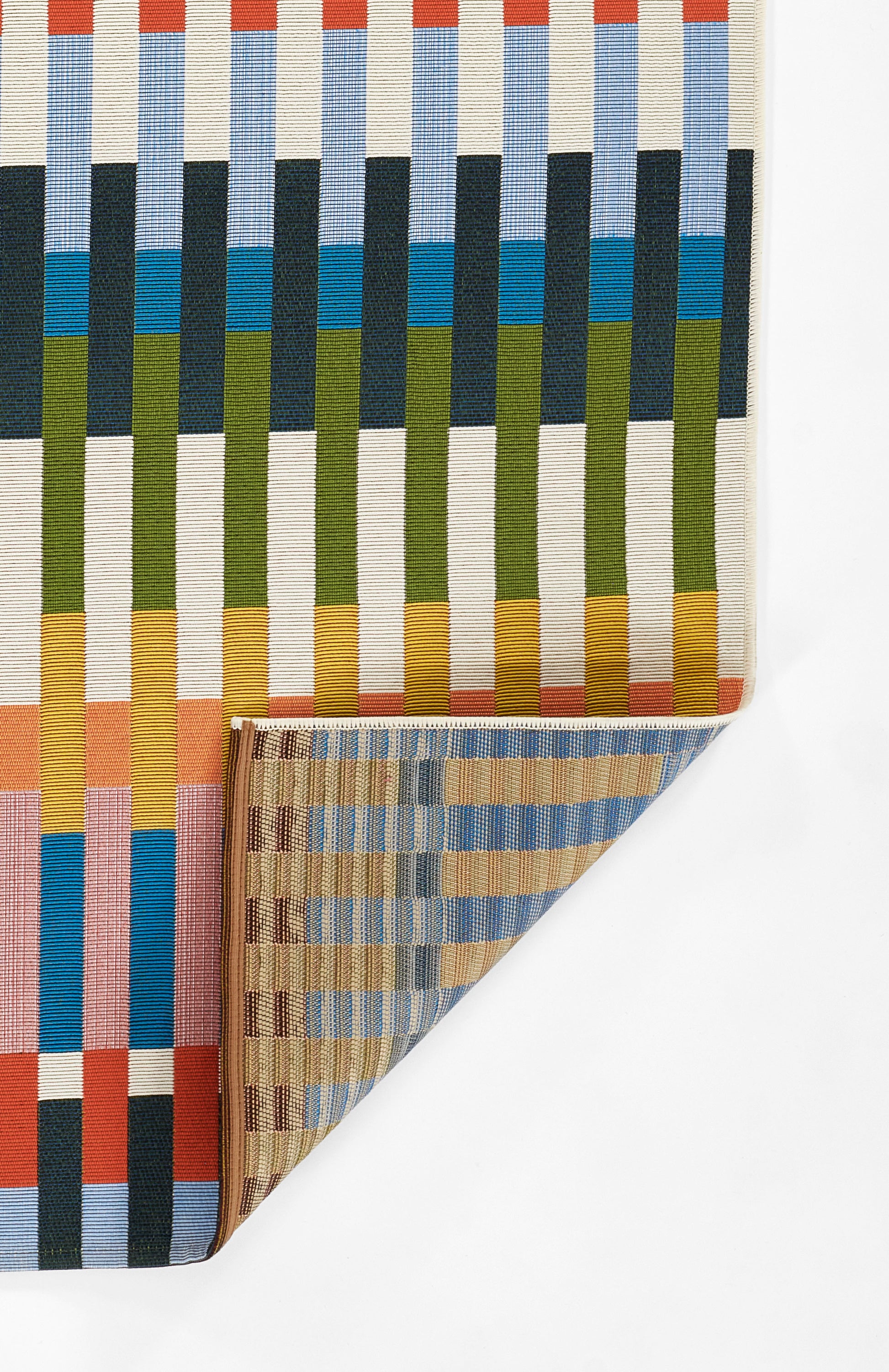 Rectangular striped woven rug with vertical ribbons in blue, green, yellow, orange; folded corner reveals tan underside.
