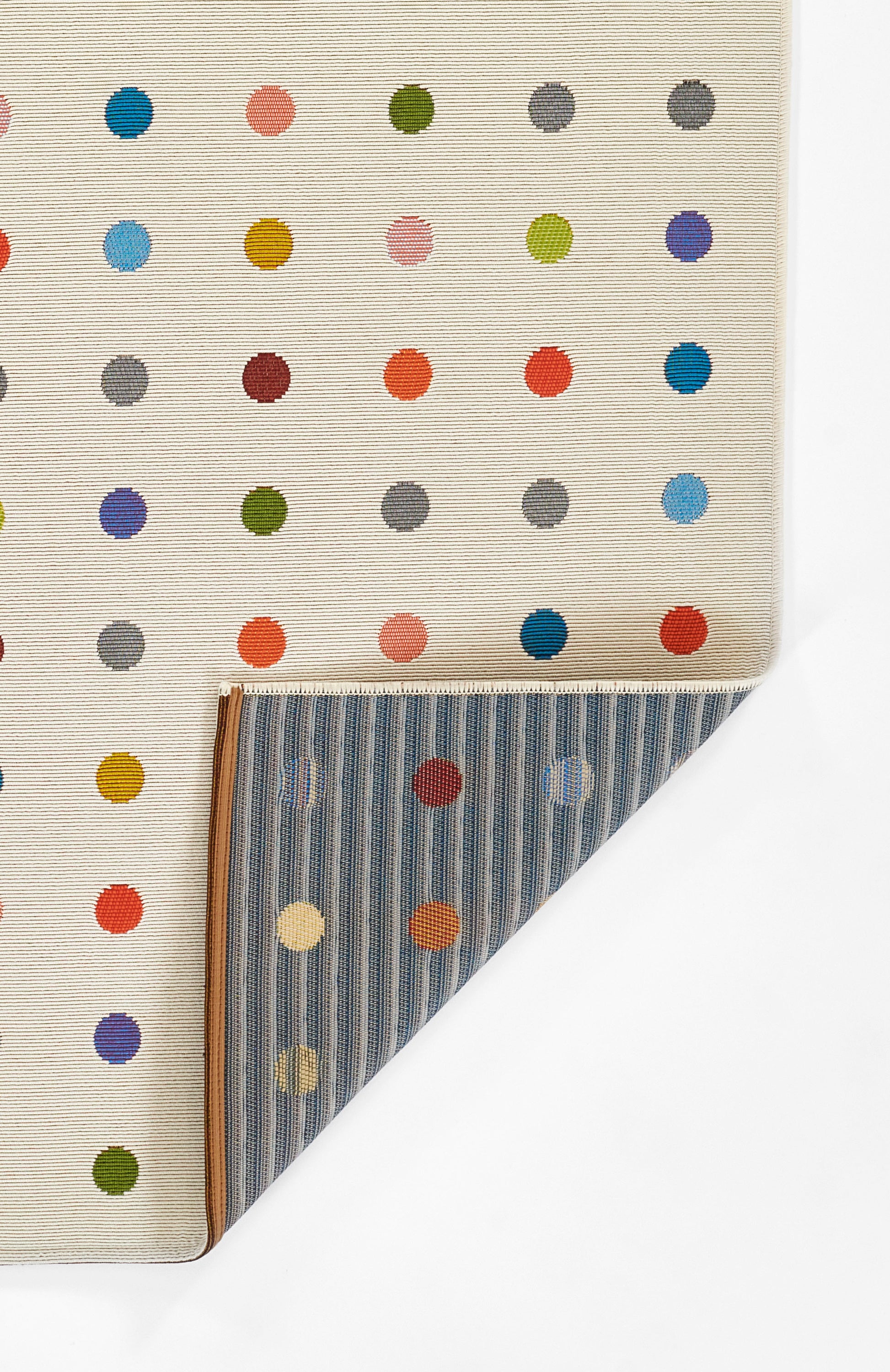 Beige rug with multicolor polka dots; folded to reveal a blue striped reverse, a reversible rug 4' x 6'.