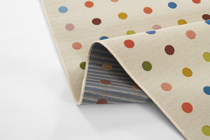 Cream rug with multicolored polka dots; rolled corner reveals blue striped underside.