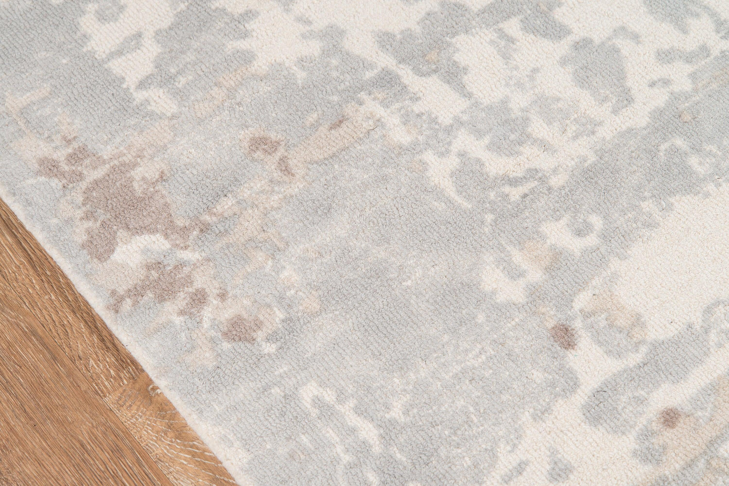Rectangular rug in soft gray and ivory with a subtle blue-taupe pattern on a wooden floor.