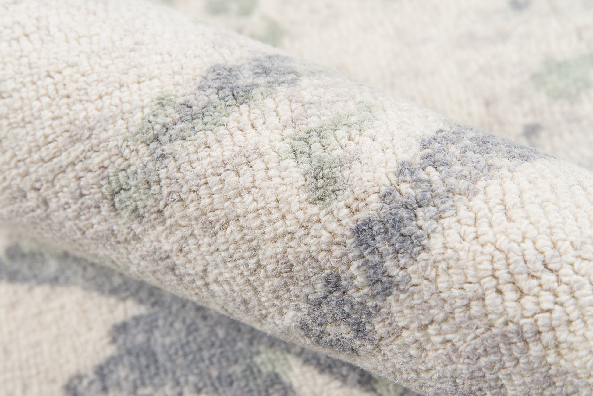 Ivory plush rug with grey and sage-green abstract pattern; textured boucle pile.