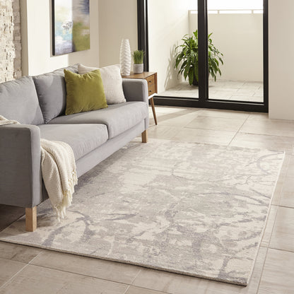 Light gray abstract-pattern area rug under a modern gray sofa with olive-green cushion in a bright living room.