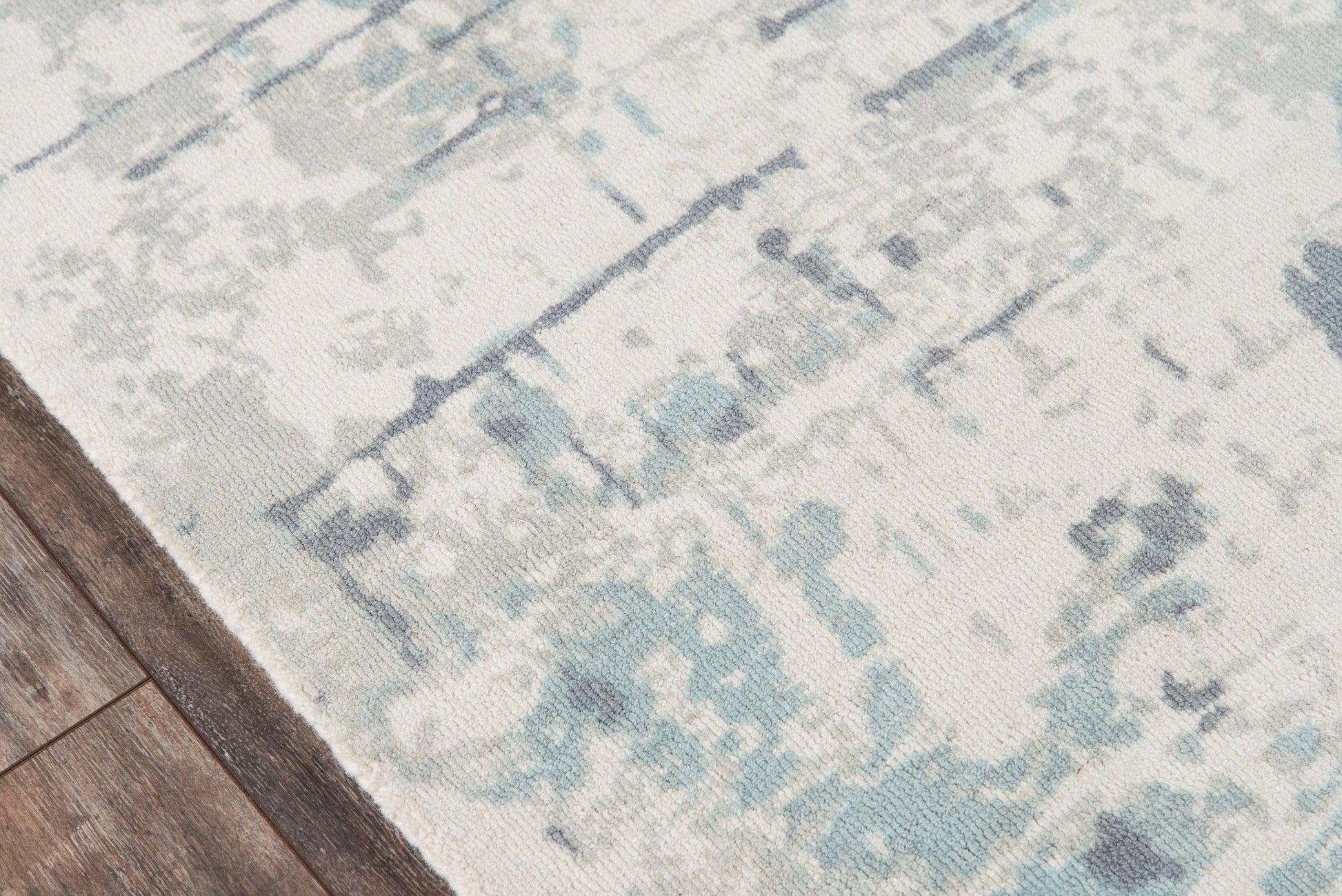 Abstract blue and ivory distressed area rug on hardwood floor.
