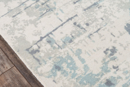 Abstract blue and ivory distressed area rug on hardwood floor.