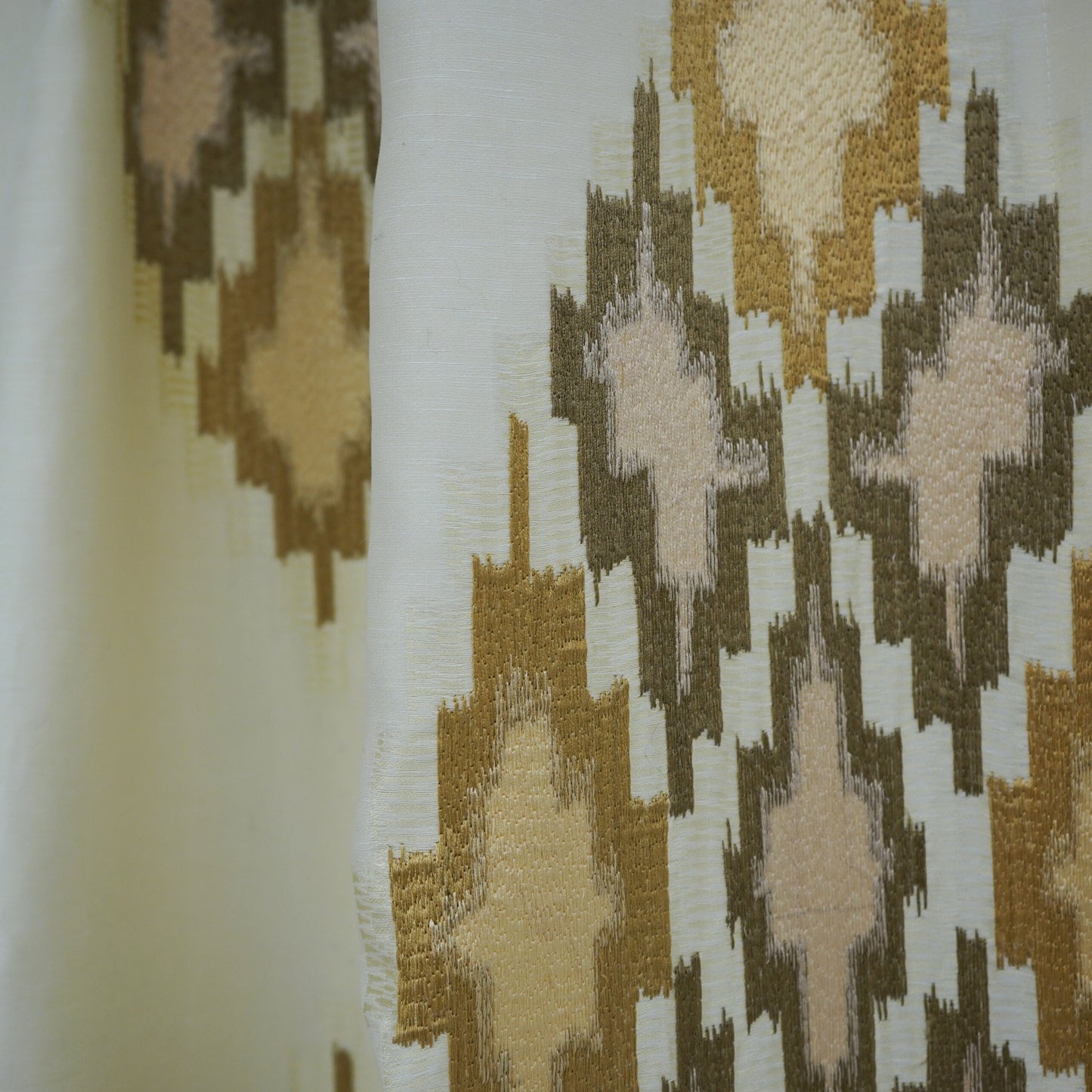 Ivory woven fabric with gold, taupe and blush geometric diamond ikat-inspired pattern.