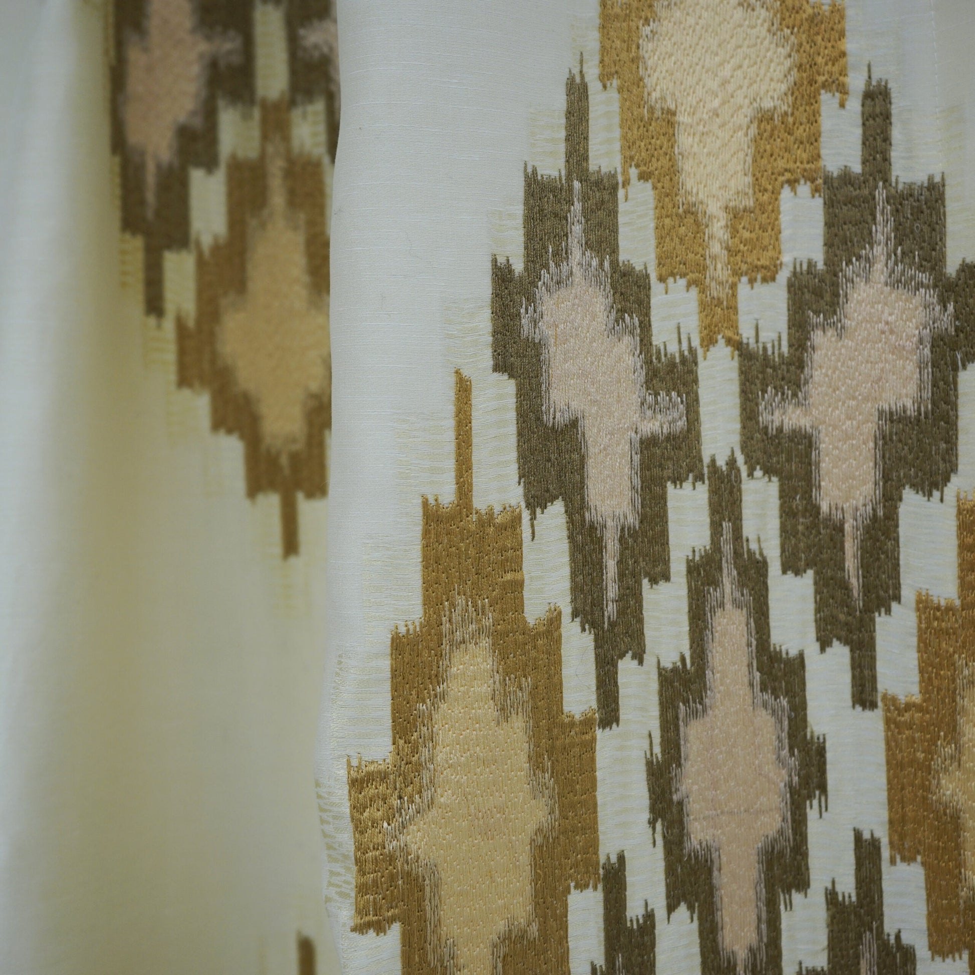Ivory woven fabric with gold, taupe and blush geometric diamond ikat-inspired pattern.