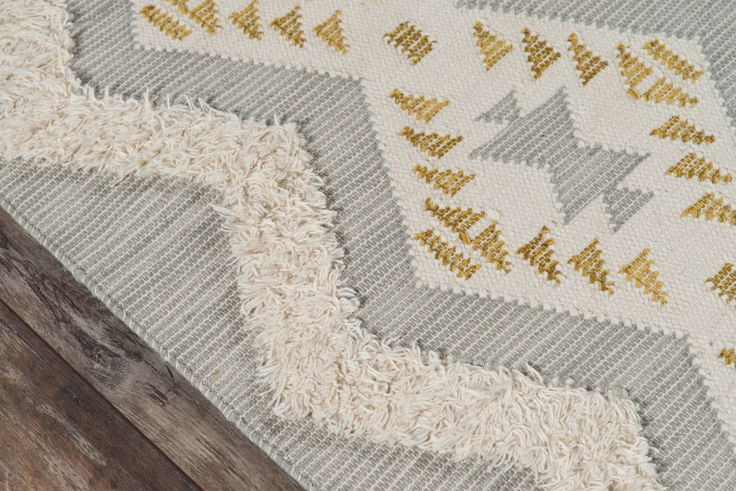 Cream fringe rug with gray geometric pattern and yellow accents; woven texture on dark wood floor.