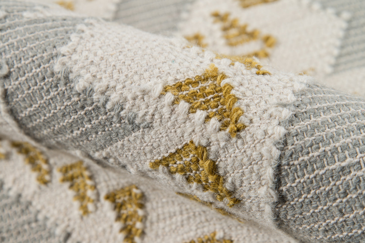 Woven gray and ivory rug with mustard yellow geometric accents, soft textured surface.