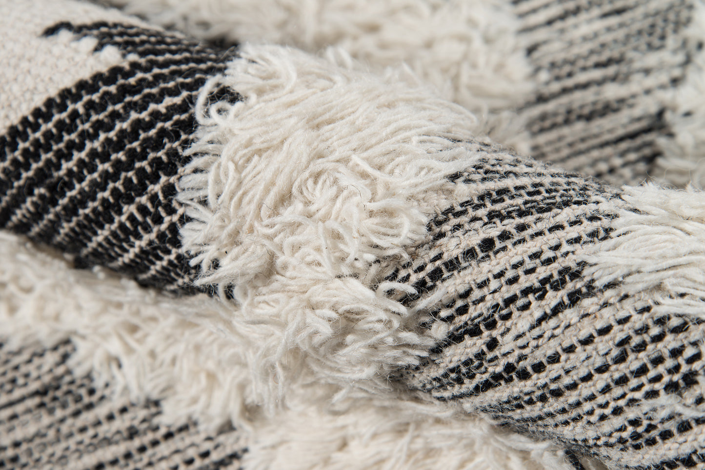 Close-up of black and ivory woven runner rug with shaggy cream fringe.