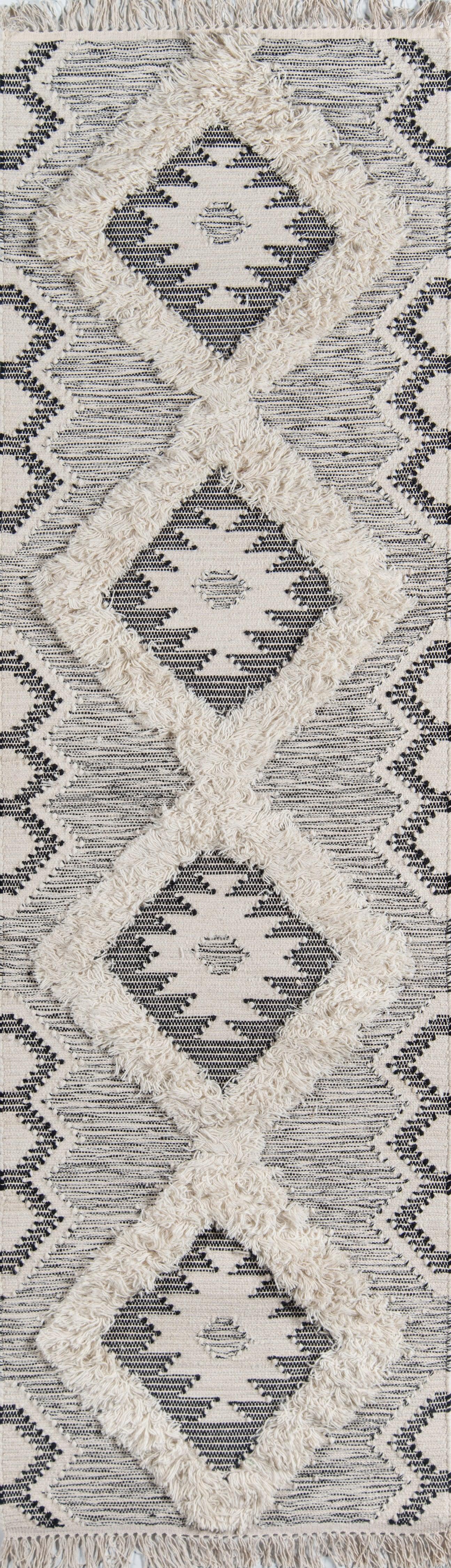 Ivory rug with navy geometric diamond pattern; plush cream shag borders and fringed edges.