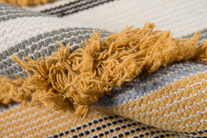 Close-up of a woven throw blanket with mustard fringe, gray and cream stripes, soft knit texture.