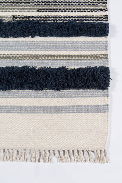 Woven striped rug in cream, navy and gray with thick navy fringe along bottom edge.