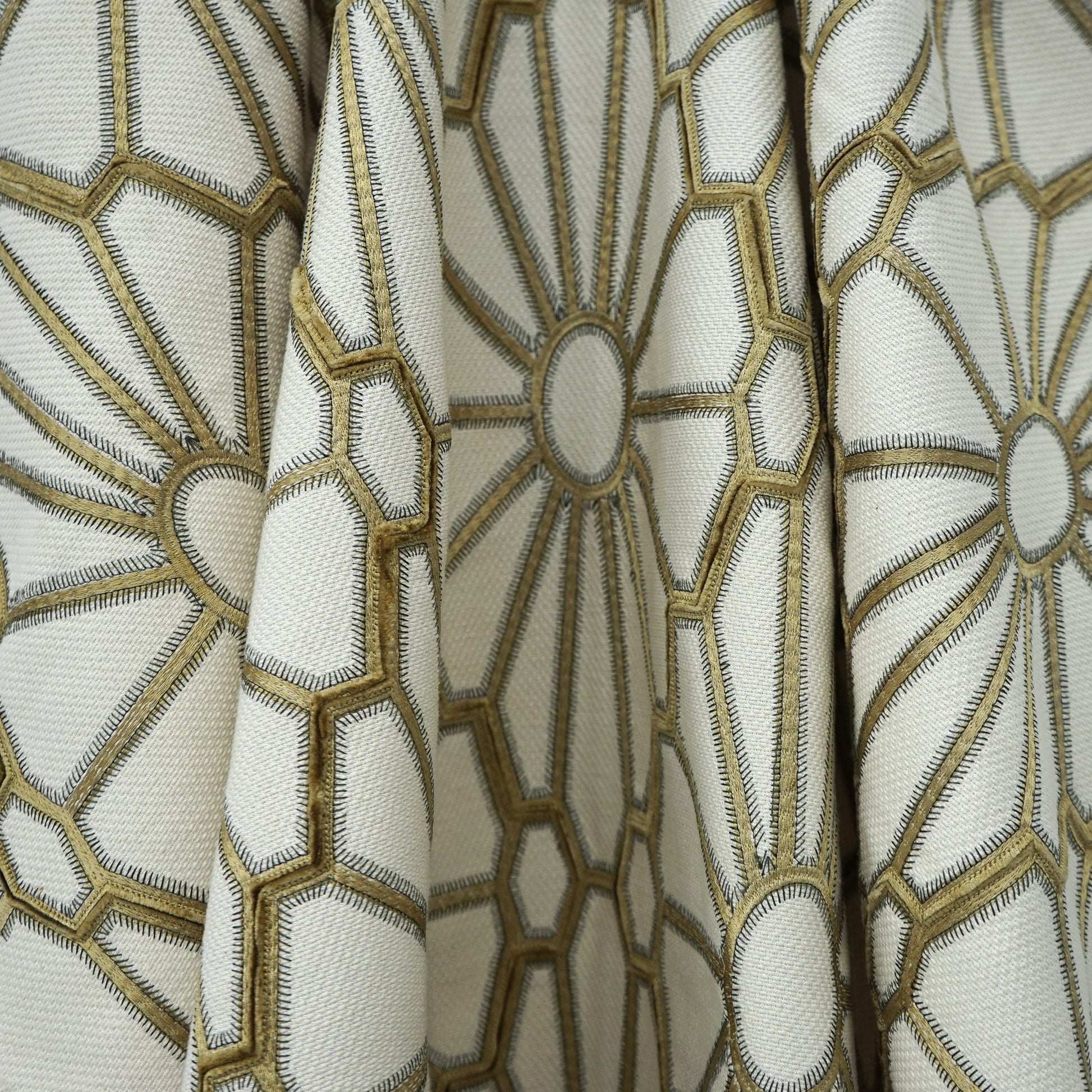 Cream drapery fabric with metallic gold embroidered geometric hexagon and circular motifs.