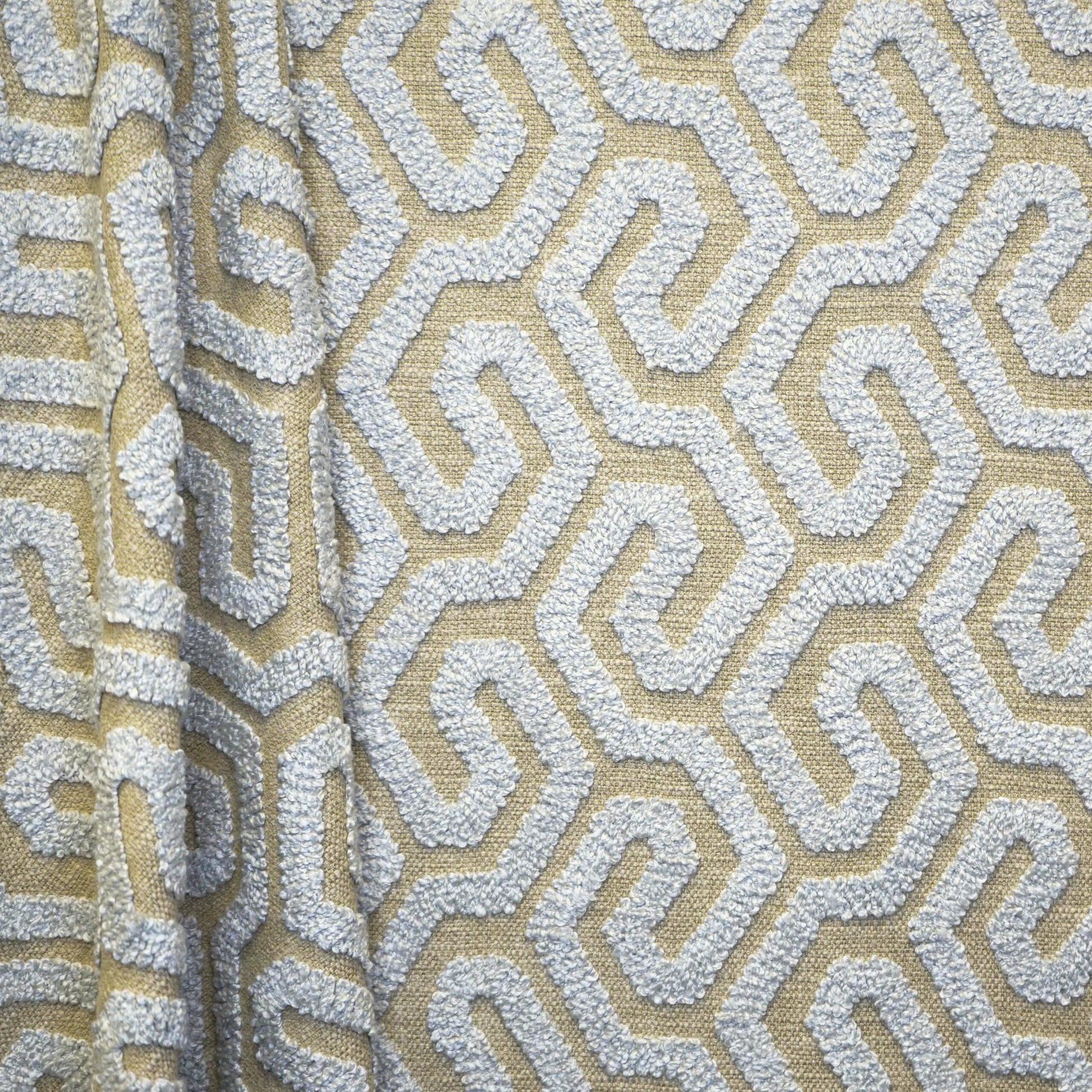Beige upholstery fabric with white textured geometric maze pattern and raised boucle texture.