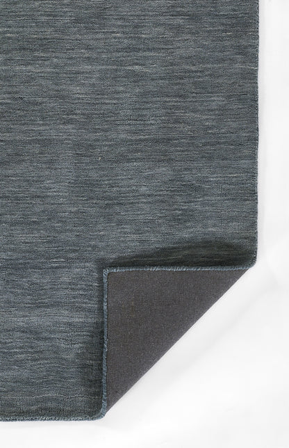 Blue-gray woven rug with textured surface and frayed edge; corner folded to reveal dark underside.