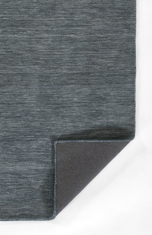 Blue-gray woven rug with textured surface and frayed edge; corner folded to reveal dark underside.