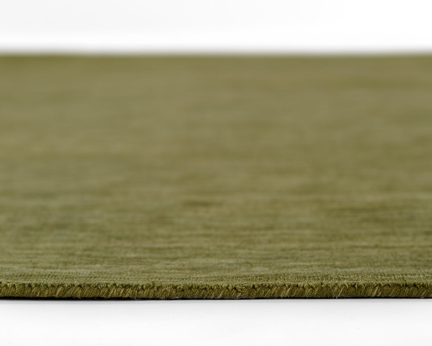 Olive green rug close-up with low-pile texture and edge fringe.