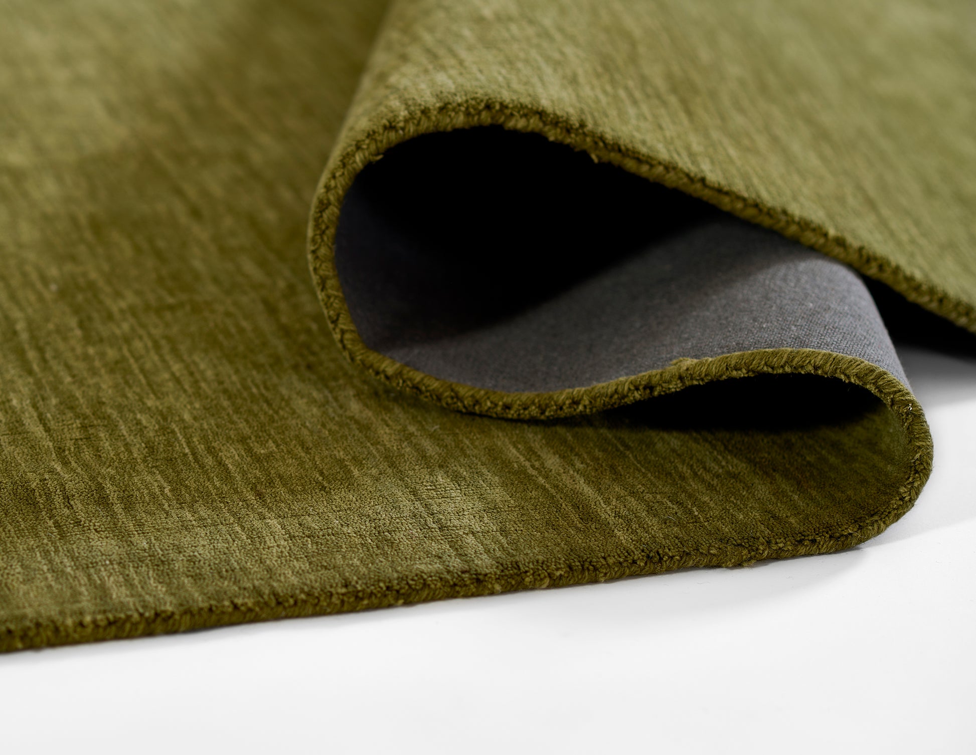 Olive green rug with suede-like pile and gray backing, curved edge; 8' x 10'.